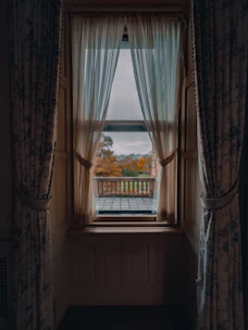 A cozy home with wooden framed sliding windows overlooking a garden in autumn.