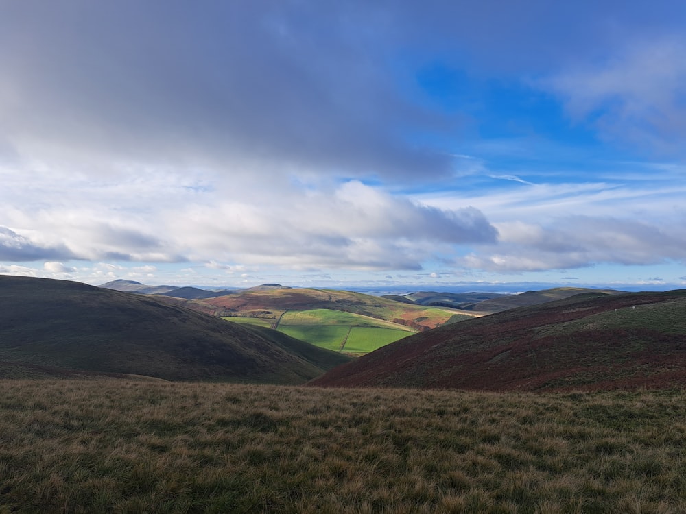 a grassy hill with rolling hills in the distance