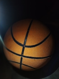 Close-up of a professional basketball with orange and black details on a wooden court.