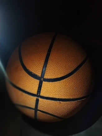 Close-up of bright orange and black basketball on a vibrant court.