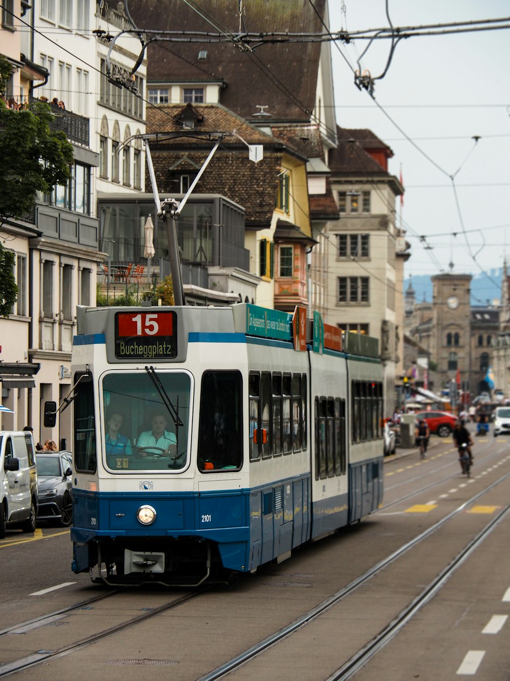 a blue and white tram traveling down a street