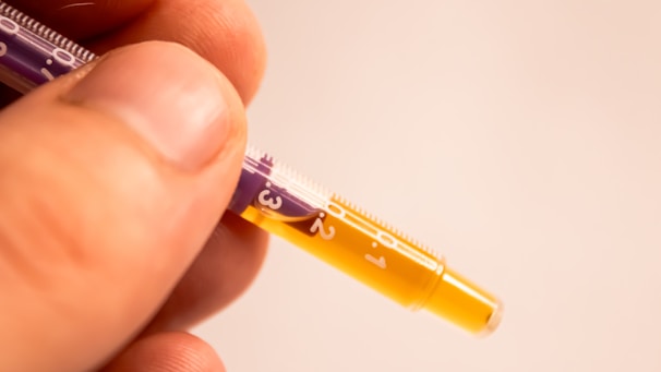 Close-up of a hand holding a vial of peptides with a syringe ready for injection.