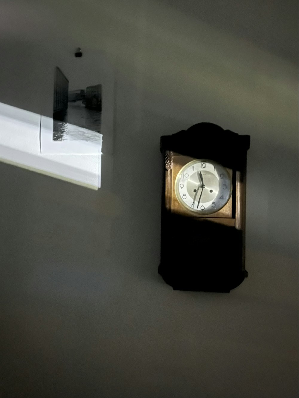 um relógio em uma parede com uma janela ao fundo