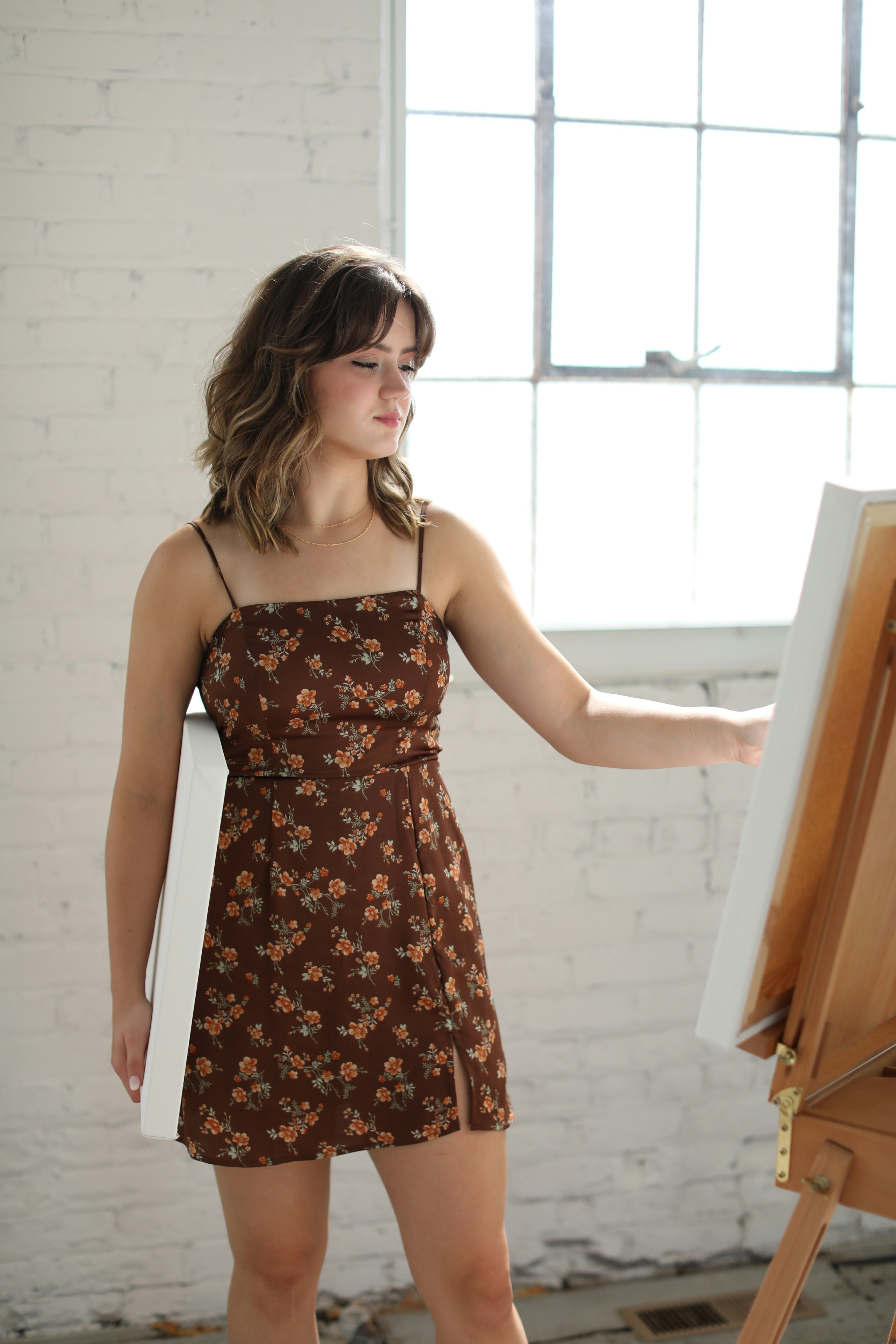 a woman standing in front of a easel holding a paintbrush