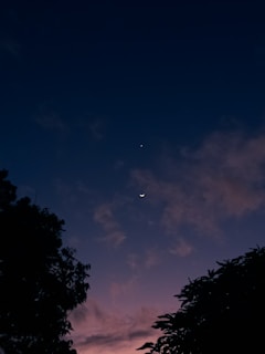 A serene night sky with twinkling stars and a glowing crescent moon, framed by subtle purple and gold hues.