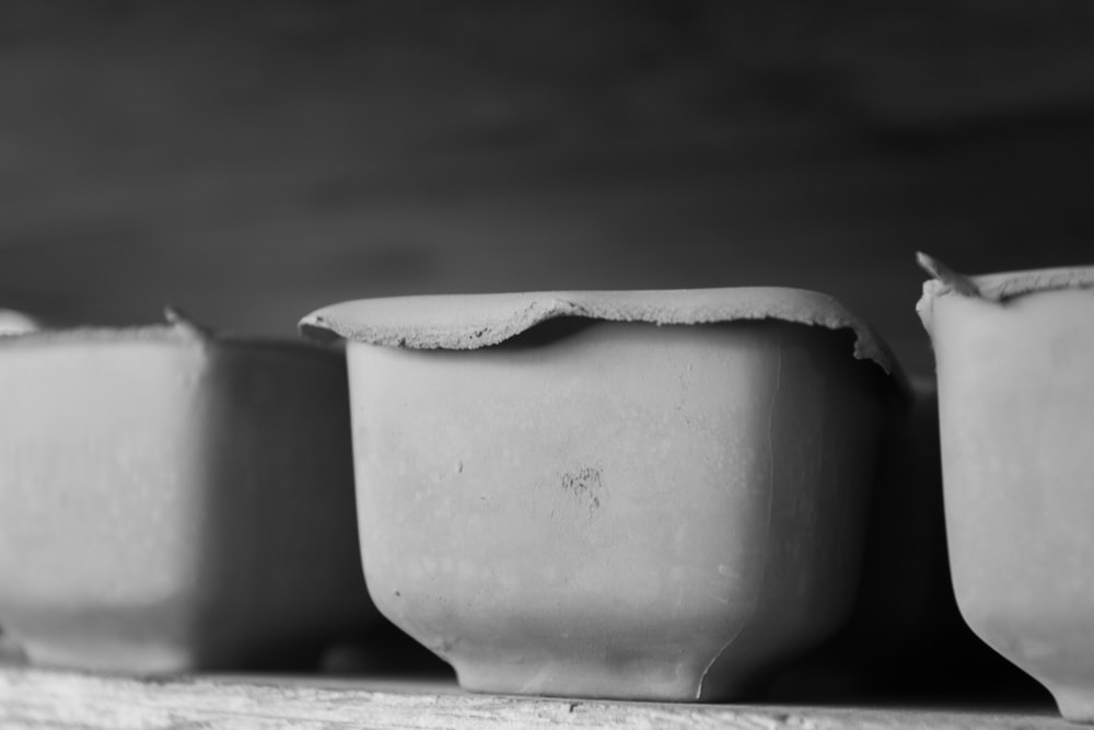 a row of white bowls sitting on top of a wooden table