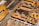 Close-up of vintage metal letterpress blocks arranged with visible woodgrain texture. The letters appear worn, indicating age and use, and are in various shades of brown and gold.
