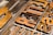 Close-up of vintage metal letterpress blocks arranged with visible woodgrain texture. The letters appear worn, indicating age and use, and are in various shades of brown and gold.