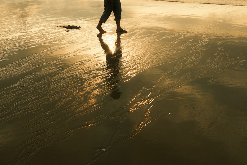 a person walking on the beach at sunset