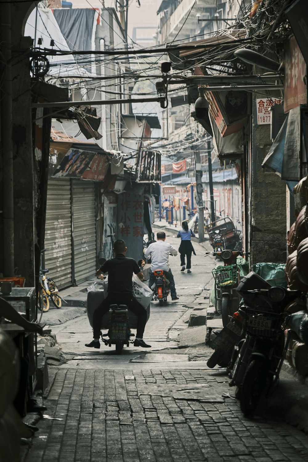 a man riding a motorcycle down a narrow street