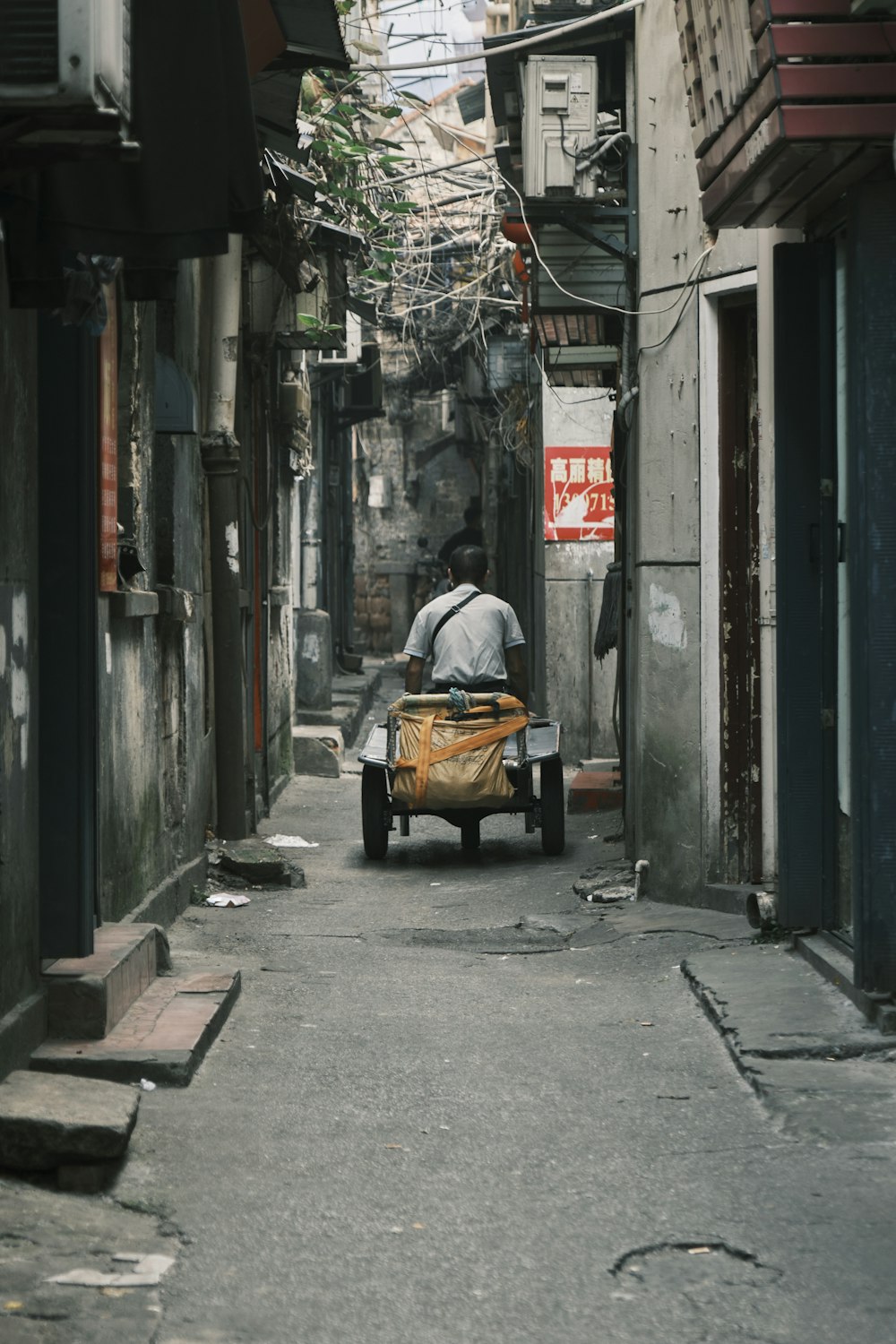 a man riding a cart down a narrow alley way