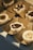 A series of desserts arranged in individual brown paper trays. Each dessert is a round, layered piece with both white and dark brown sections, possibly made of steamed rice flour and brown sugar. Some are topped with red bean paste and others with small granular toppings.
