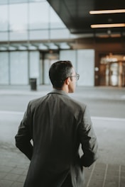 A private detective in a navy blue suit observing a cityscape at dusk, symbolizing vigilance and professionalism.