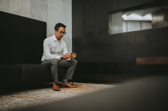 a man sitting on a couch looking at his cell phone