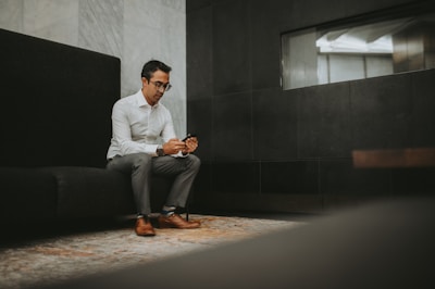a man sitting on a couch looking at his cell phone