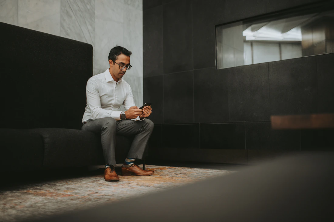 Homem sentado no sofá pesquisando no celular