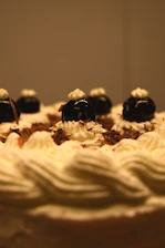 Close-up of a hand delicately decorating a rich chocolate cake with fresh berries and edible gold flakes.
