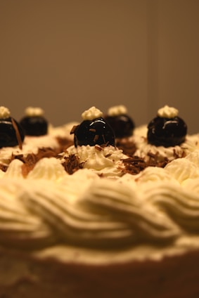 A close-up of an elegant multi-tiered cake adorned with fresh fruits and delicate chocolate decorations.