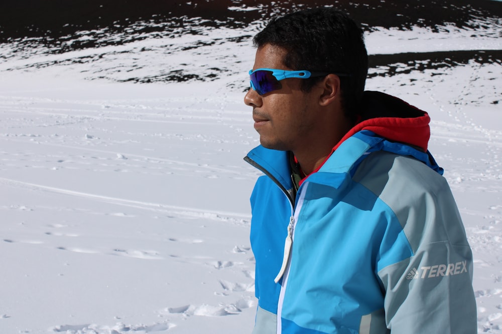 a man standing in the snow wearing sunglasses