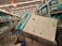 A shopping aisle filled with shelves stacked with boxes of diapers. A large box labeled 'Evenflo Omni Plus' is prominently placed in a shopping cart. Other diaper brands such as Pampers are visible on the shelves. The setting appears to be a supermarket or a retail store with fluorescent lighting.