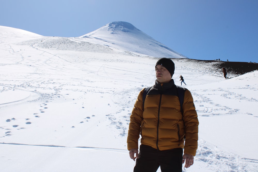 a man standing in the snow in front of a mountain