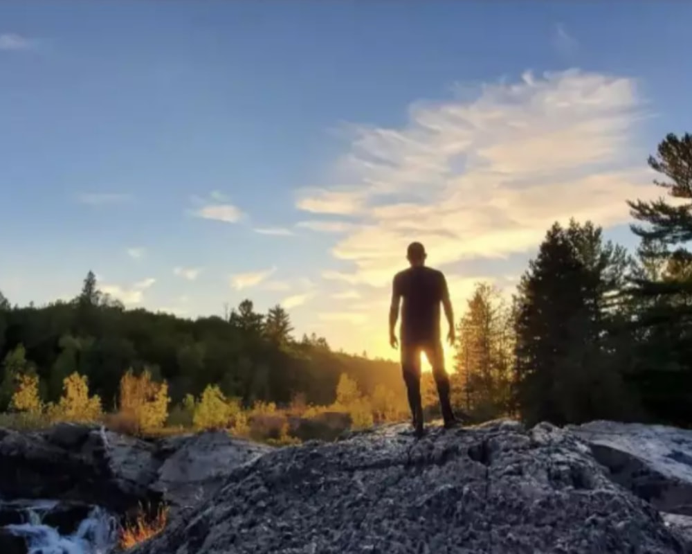 a man standing on top of a large rock