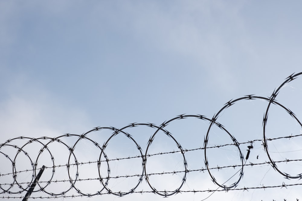 a barbed wire fence with a blue sky in the background