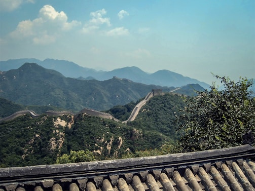A vibrant sunset view of the Great Wall of China winding over lush green hills.