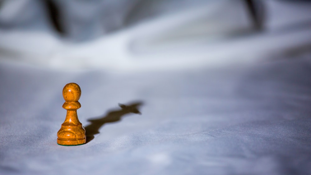 a wooden chess piece casting a shadow on a white surface