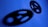 Two interconnected gears are set against a blue background, casting dark shadows that feature distinct shapes and cutouts.