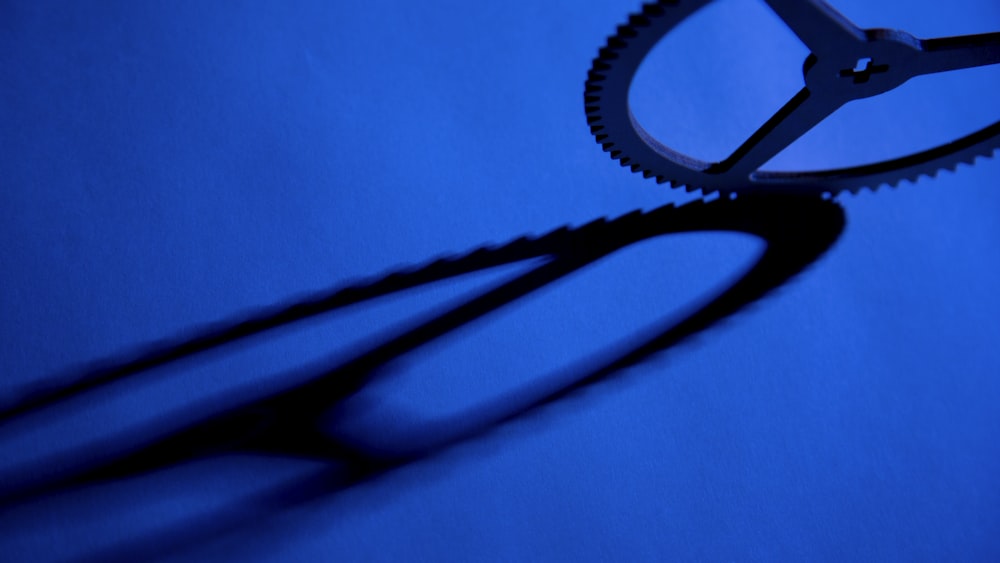 a pair of scissors casting a shadow on a blue surface