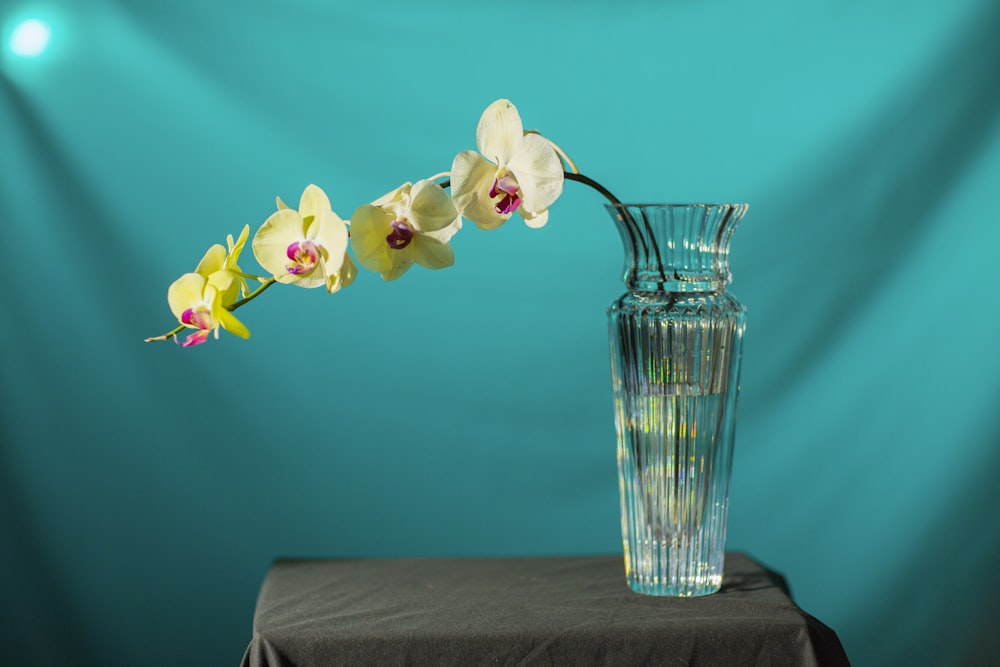 un vase en verre avec des fleurs dedans sur une table