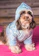 A small dog wearing a cozy turquoise handmade sweater, sitting happily on a colorful cushion.