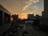 Sunset view of a construction site with heavy machinery and a city skyline.