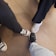 The image shows three people standing together, each displaying one foot in the center. The footwear includes a pair of black Converse sneakers, a pair of gray slip-on sneakers, and a pair of black athletic shoes. The flooring is composed of large, square, brown tiles.