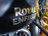Close-up of a matte black Royal Enfield with royal gold accents in a workshop setting.