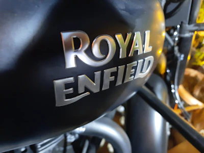Close-up of a matte black Royal Enfield with royal gold accents in a workshop setting.