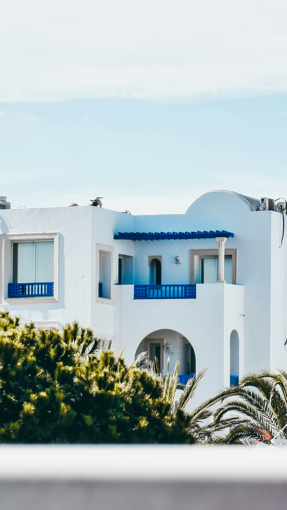 a white building with blue balconies and trees