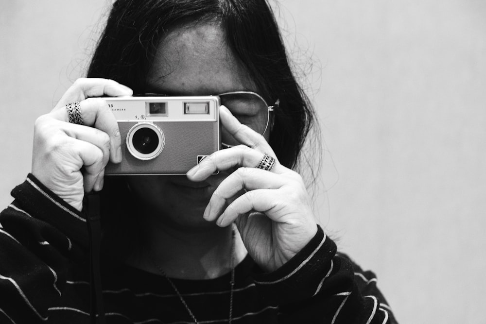 a woman holding a camera up to her face