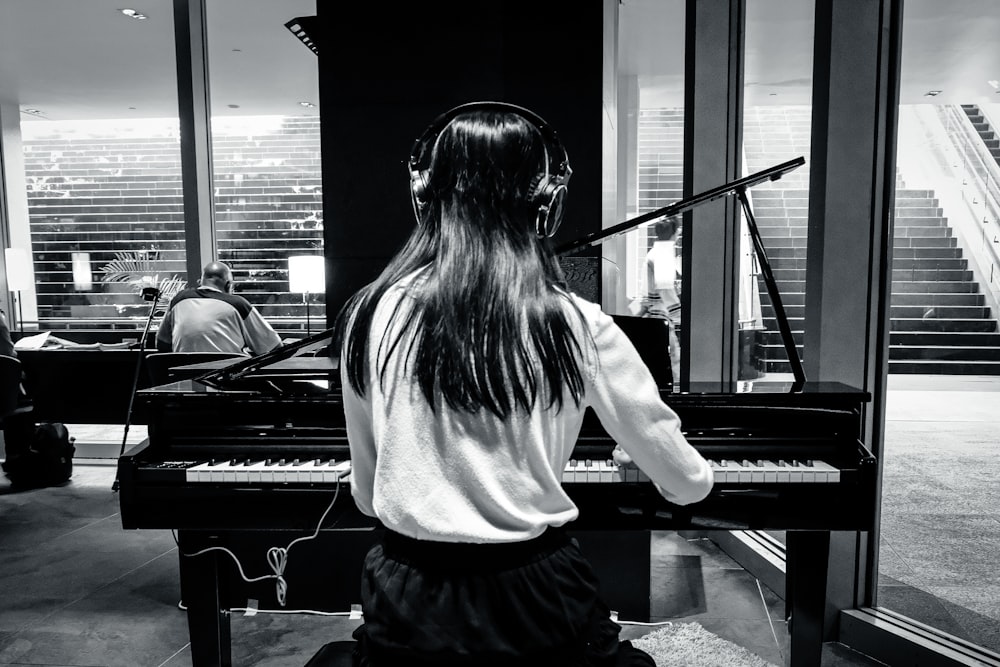 a woman sitting at a piano with headphones on