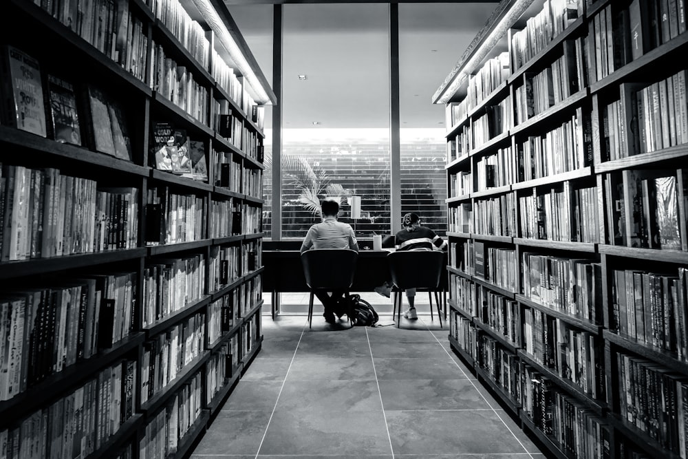 a person sitting at a desk in a library filled with books