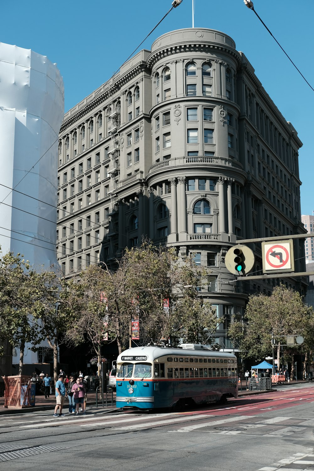 a blue and white bus driving down a street next to a tall building