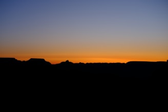 A horizon at twilight with muted gold and charcoal hues blending into starlit sky.