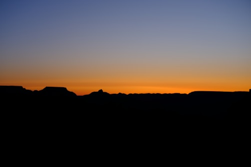 A horizon at twilight with muted gold and charcoal hues blending into starlit sky.