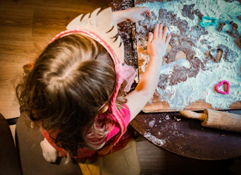 a little girl is making a doughnut on a table