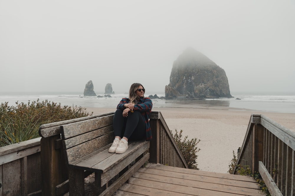 a woman sitting on a bench on a foggy day