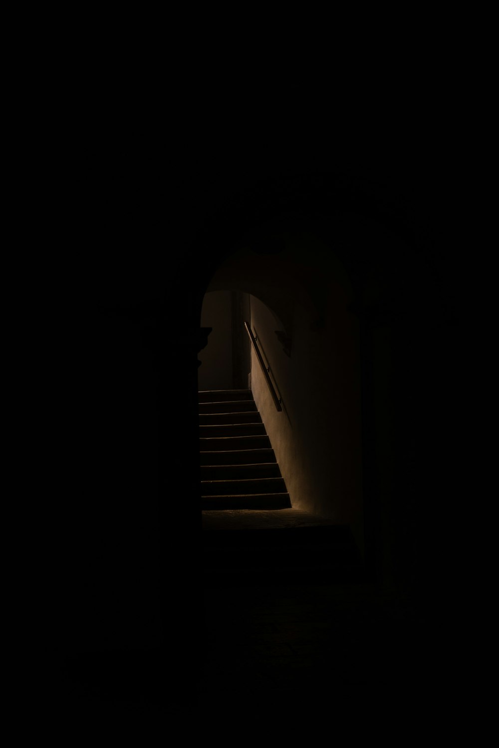 um corredor escuro com escadas e uma luz no final