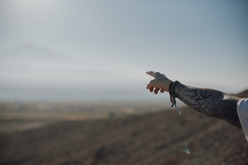 a man with a tattoo on his arm pointing at something