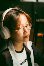 An artist smiling while listening to their track on headphones in a cozy room.