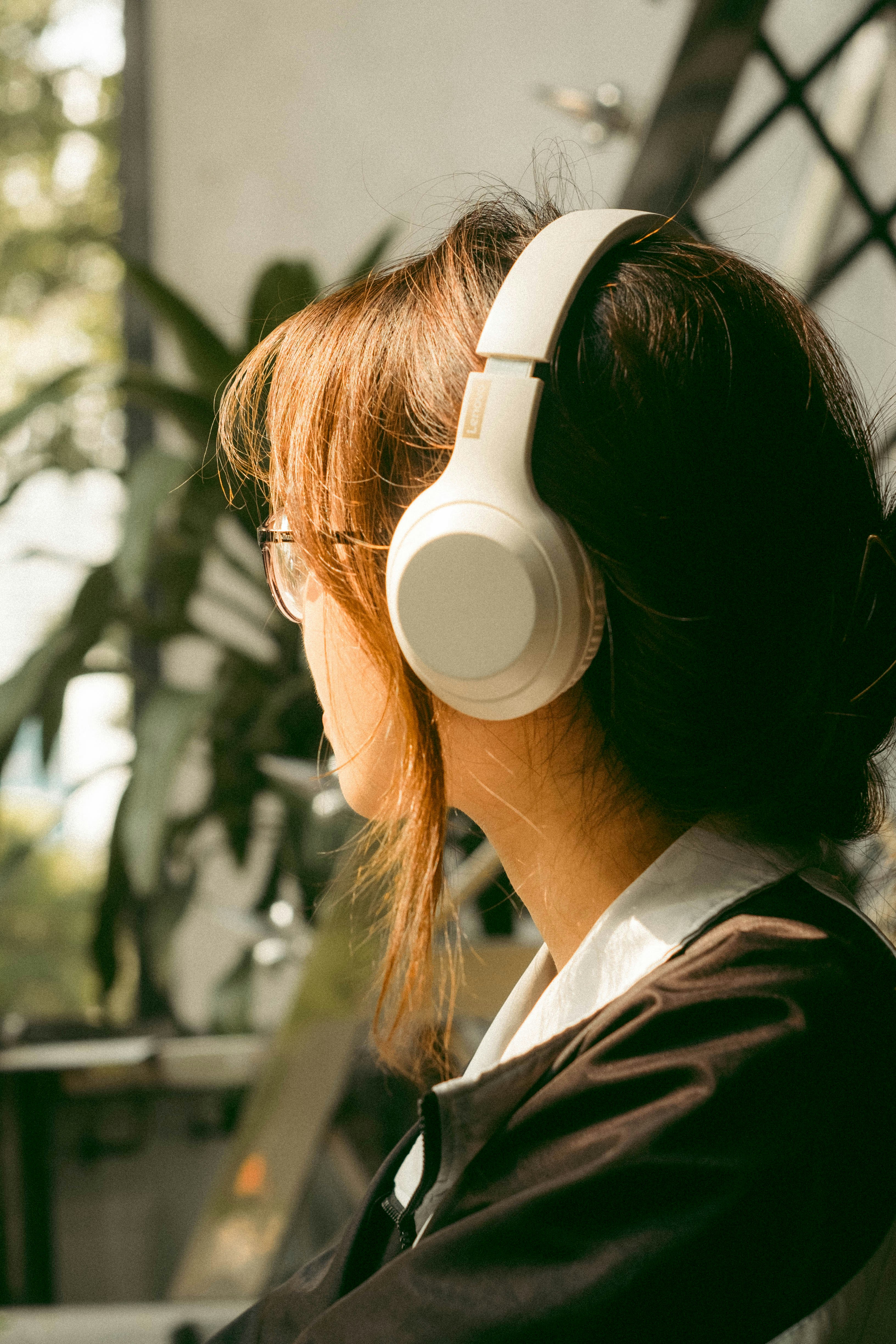 a woman wearing headphones sitting in front of a plant